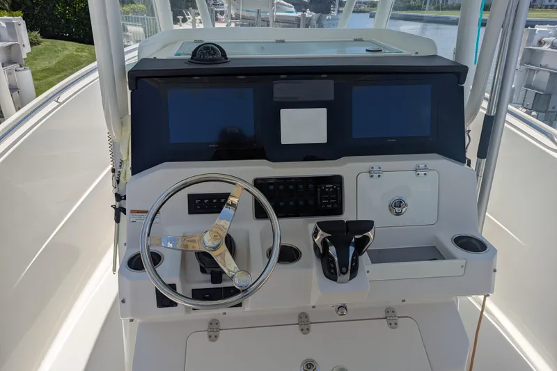 Slide: The Image of 2023 Sailfish 290 CC boat dashboard with steering wheel and navigation screens. - 4
