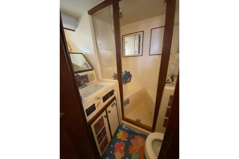 Slide: The Image of 1984 Hatteras 46 Convertible yacht bathroom with shower, sink, and colorful marine-themed decor. - 10