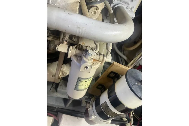 Slide: The Image of Engine components of a 1984 Hatteras 46 Convertible boat, featuring filters and pipes. - 50
