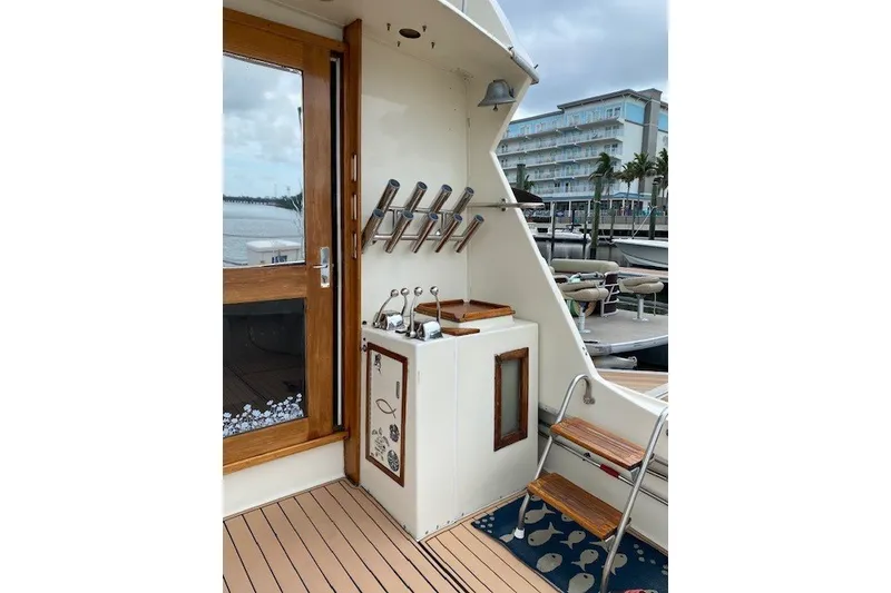 Slide: The Image of 1984 Hatteras 46 Convertible yacht deck with fishing rod holders and wooden accents. - 38