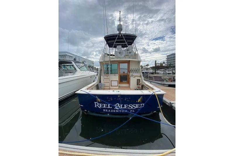 Slide: The Image of 1984 Hatteras 46 Convertible yacht docked, rear view, with "Reel Blessed" name visible. - 0