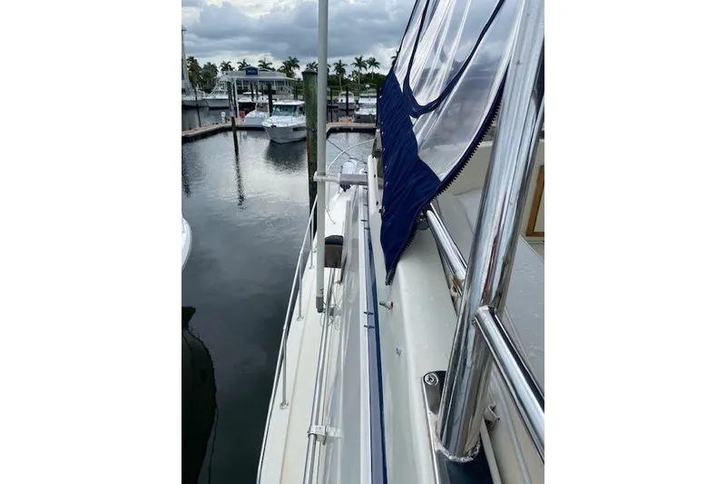 Slide: The Image of 1984 Hatteras 46 Convertible yacht docked at marina, featuring sleek railing and canopy. - 33