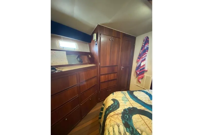 Slide: The Image of Interior of 1984 Hatteras 46 Convertible with wooden cabinetry and nautical-themed bedding. - 9