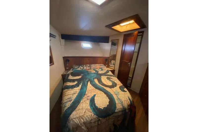 Slide: The Image of 1984 Hatteras 46 Convertible cabin with octopus-themed bedding and wooden interior. - 7
