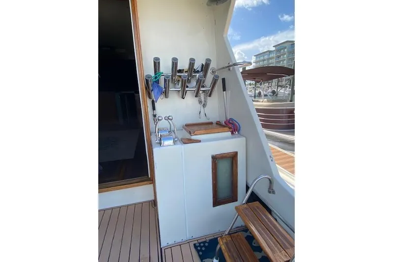 Slide: The Image of 1984 Hatteras 46 Convertible yacht deck with fishing rod holders and wooden steps. - 4