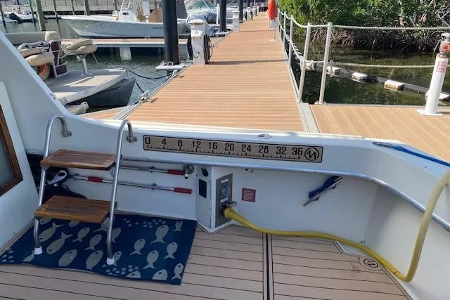 Slide: The Image of 1984 Hatteras 46 Convertible yacht docked, featuring a fishing ruler and wooden steps. - 6