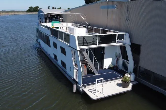 Slide: The Image of Houseboat docked by a building, Fun Country 56 model, 1997, on calm water. - 4