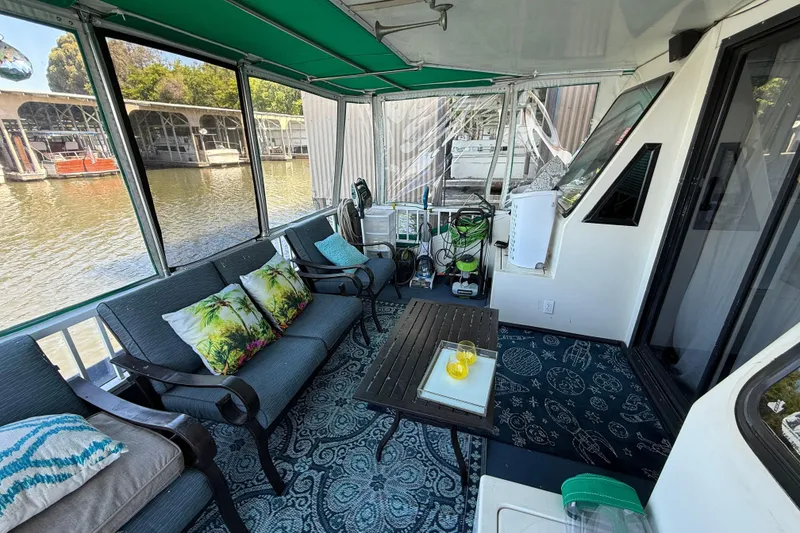 Slide: The Image of Houseboat deck with cozy seating, tropical cushions, and a scenic waterfront view. Fun Country 56, 1997. - 12
