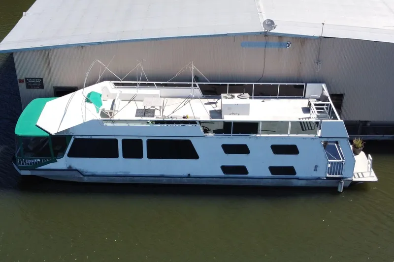 The Image of Houseboat docked beside a building, Fun Country 56 model, 1997, with green canopy. - 1