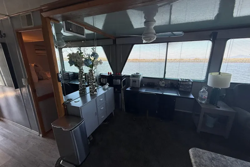 Slide: The Image of Interior of a 1997 Fun Country model 56 houseboat with desk, flowers, and lake view. - 18