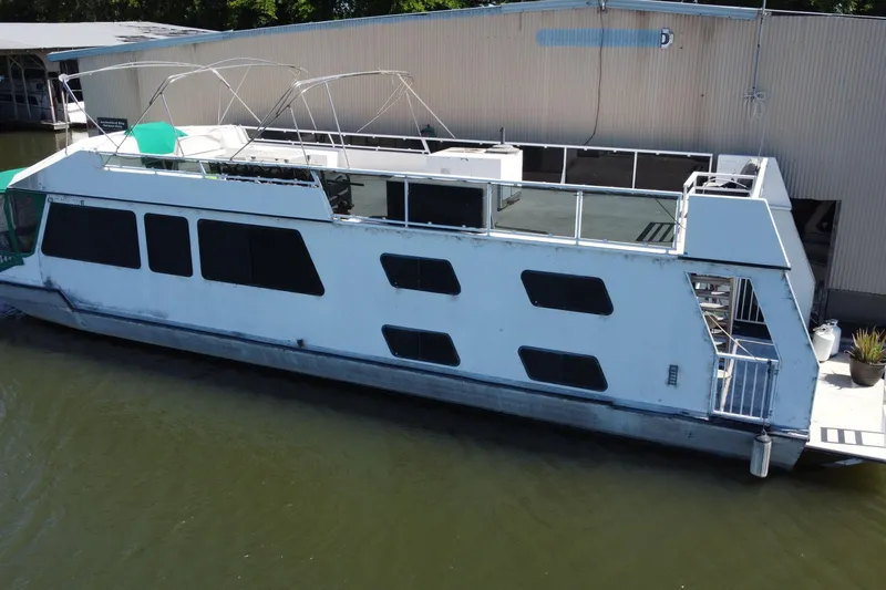 Slide: The Image of Houseboat docked by a building, Fun Country 56 model, 1997, with upper deck and windows. - 3