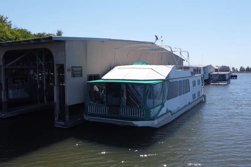 Slide: The Image of Houseboat docked at marina, Fun Country 56 model, 1997, with green accents and covered deck. - 5