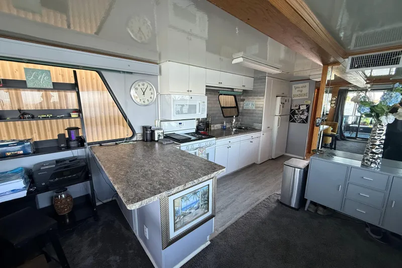 Slide: The Image of Modern kitchen interior in a 1997 Fun Country 56 houseboat, featuring white cabinets and a granite countertop. - 21