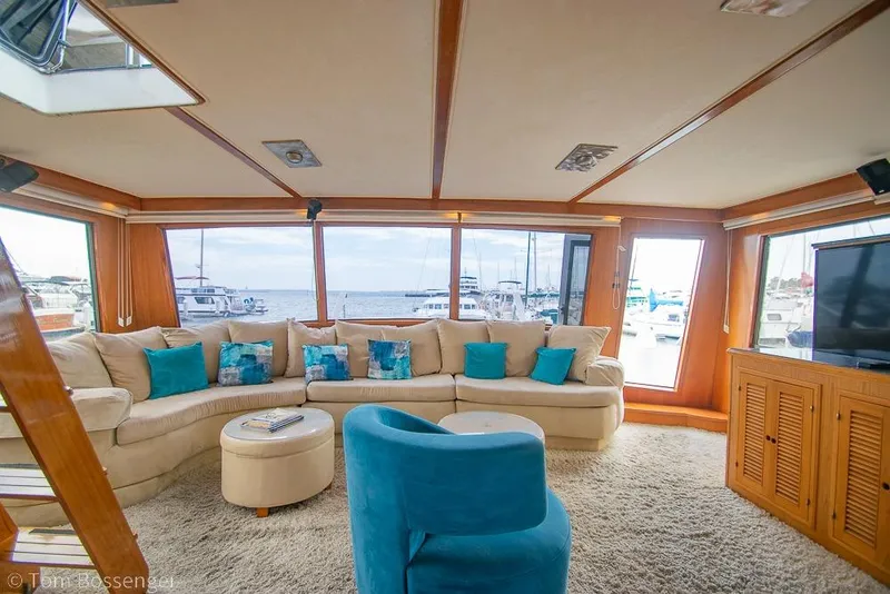 Slide: The Image of Luxurious 1990 Kha Shing Flush Deck Motor Yacht interior with plush seating and scenic marina views. - 10