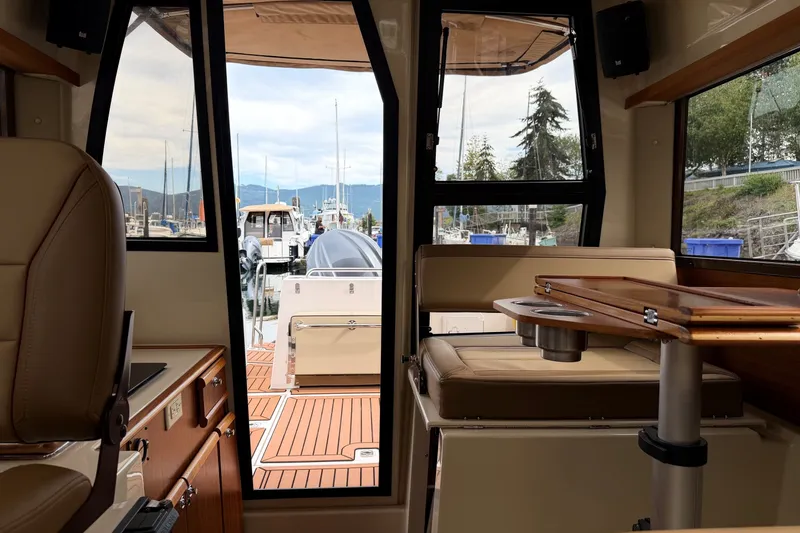 Slide: The Image of Interior view of 2023 Ranger Tugs R-25 boat, featuring seating and a wooden table. - 17