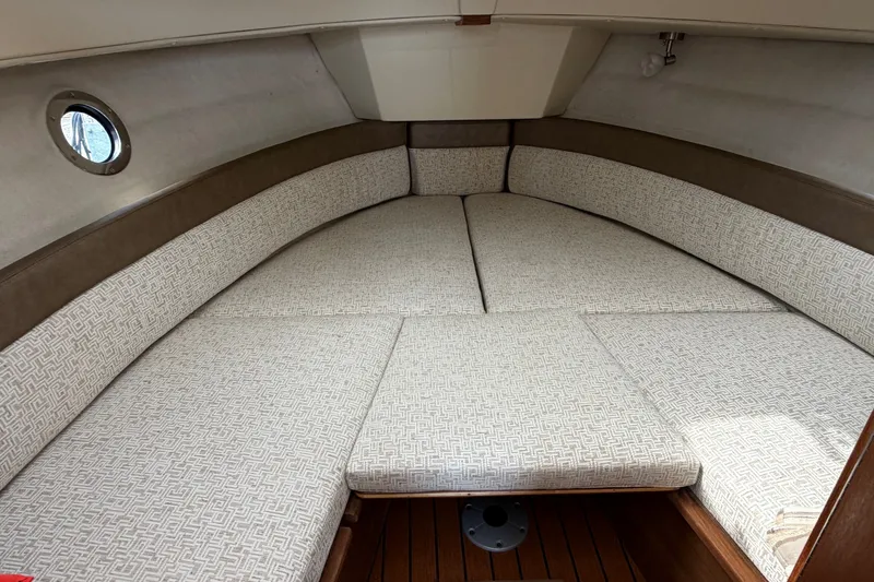 Slide: The Image of 2023 Ranger Tugs R-25 cabin interior with cushioned seating and wooden flooring. - 18