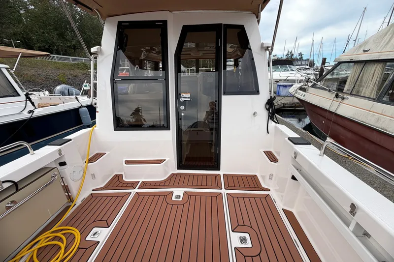 Slide: The Image of 2023 Ranger Tugs R-25 boat deck with teak flooring at a marina. - 7