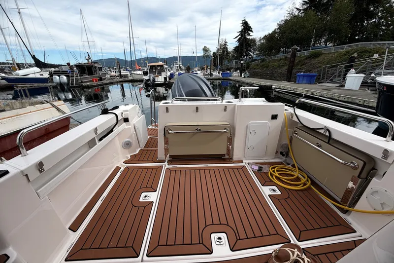 Slide: The Image of 2023 Ranger Tugs R-25 boat deck at marina, featuring wood-like flooring and docked boats. - 22