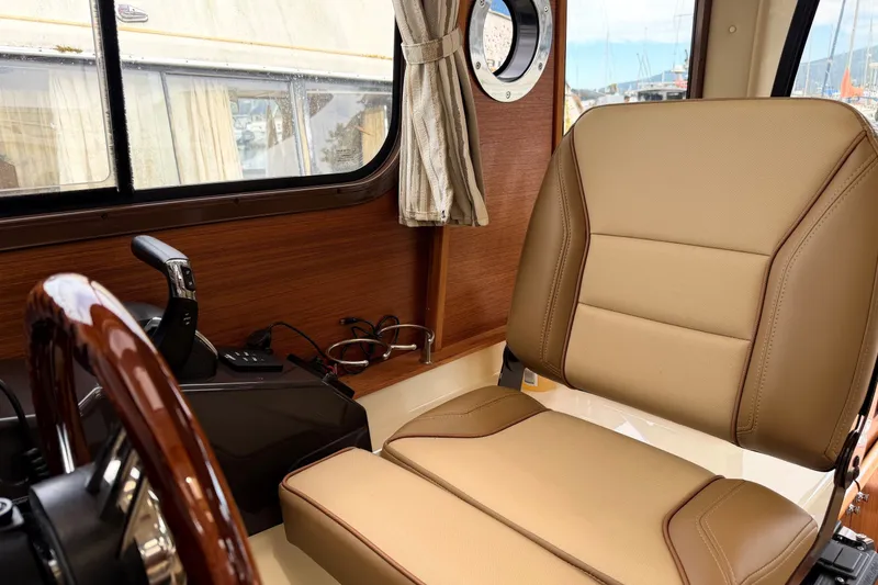 Slide: The Image of Interior of 2023 Ranger Tugs R-25 boat with tan leather seating and wooden accents. - 14