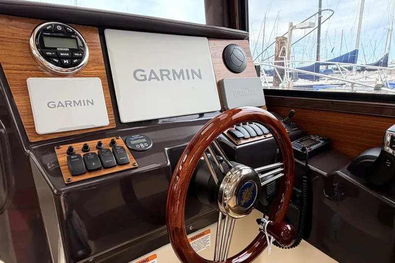 Slide: The Image of 2023 Ranger Tugs R-25 helm with Garmin navigation, wooden steering wheel, and Yamaha controls. - 12