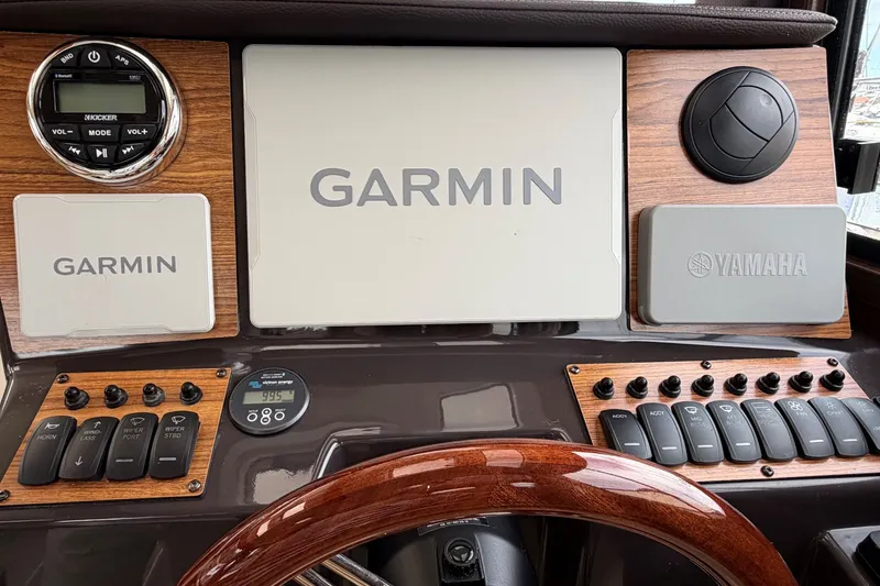 Slide: The Image of 2023 Ranger Tugs R-25 dashboard featuring Garmin and Yamaha controls with wood accents. - 13
