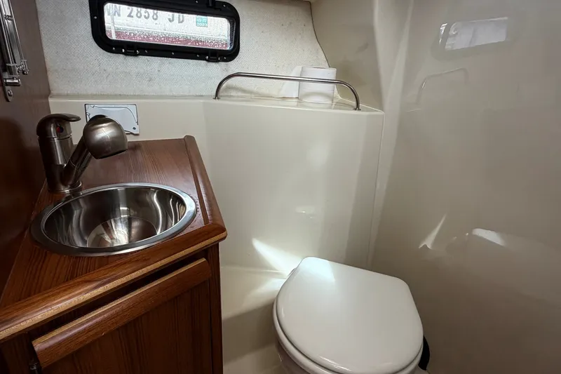 Slide: The Image of 2023 Ranger Tugs R-25 boat bathroom with sink and toilet, compact and modern design. - 19