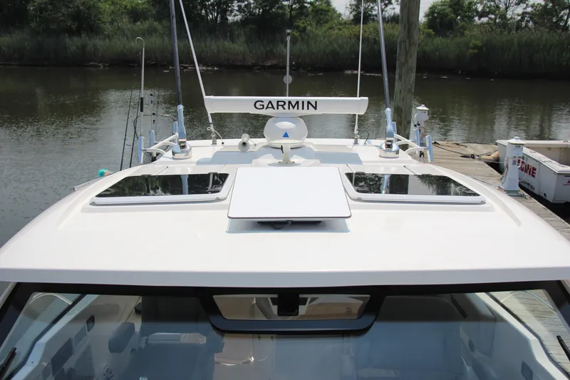 Slide: The Image of 2024 Pursuit OS 405 Offshore boat with Garmin radar, docked by a serene riverbank. - 7