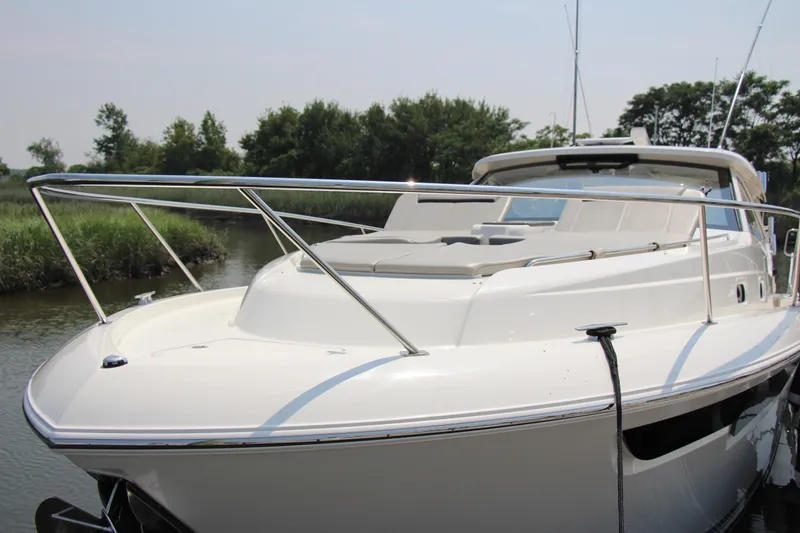 Slide: The Image of 2024 Pursuit OS 405 Offshore boat docked in a serene, lush riverside setting. - 5
