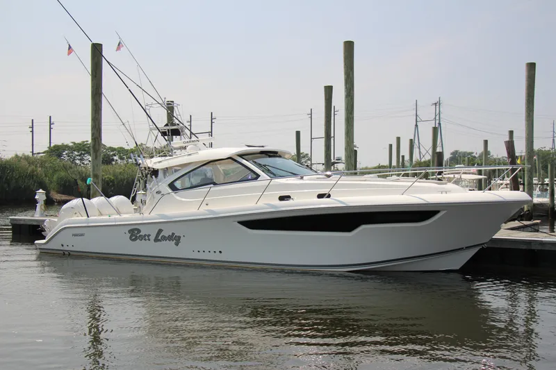 Slide: The Image of 2024 Pursuit OS 405 Offshore boat docked at marina, sleek design, white exterior. - 3