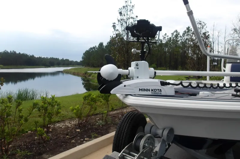 Slide: The Image of 2025 Mako 18 Pro Skiff Patriot Edition with Minn Kota Terrova motor by a scenic lake. - 8