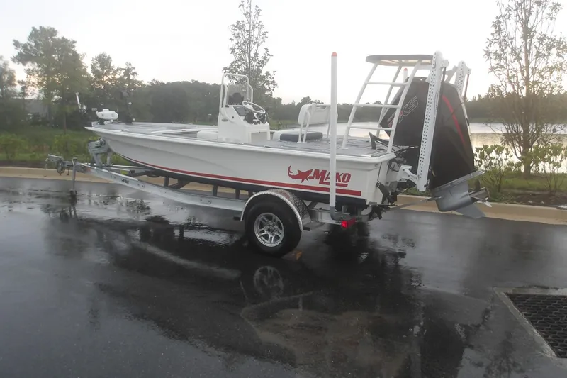 Slide: The Image of 2025 Mako 18 Pro Skiff Patriot Edition boat on trailer, parked on wet pavement. - 1