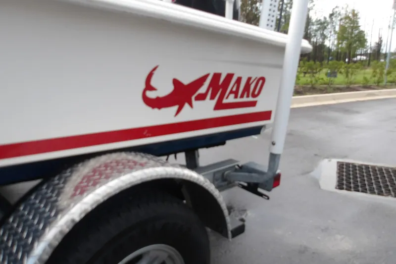 Slide: The Image of 2025 Mako 18 Pro Skiff Patriot Edition boat on trailer, featuring logo and red stripe. - 14