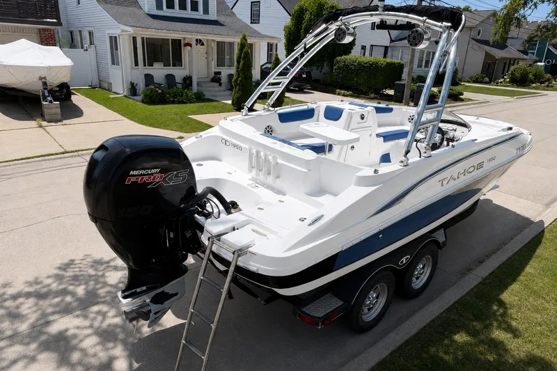 Slide: The Image of 2019 Tahoe 1950 boat with Mercury Pro XS engine parked on a trailer in a residential area. - 1