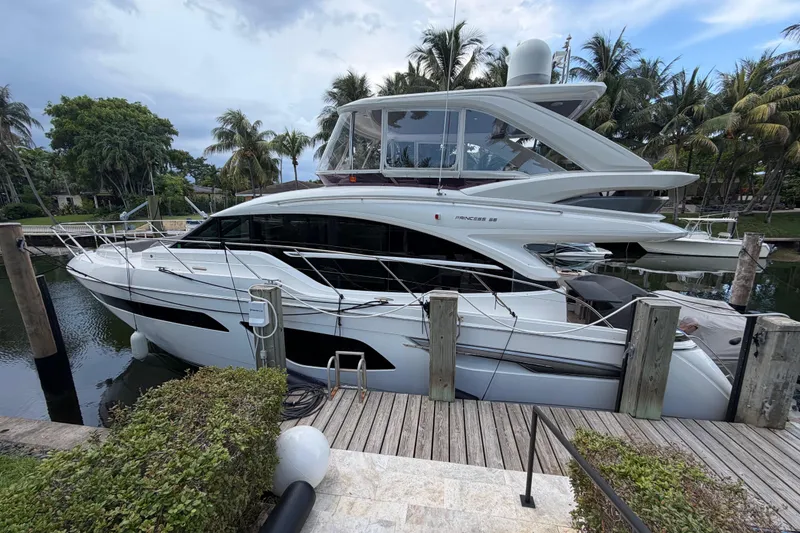 Slide: The Image of Luxurious 2018 Princess F55 yacht docked, surrounded by lush palm trees and calm waters. - 1