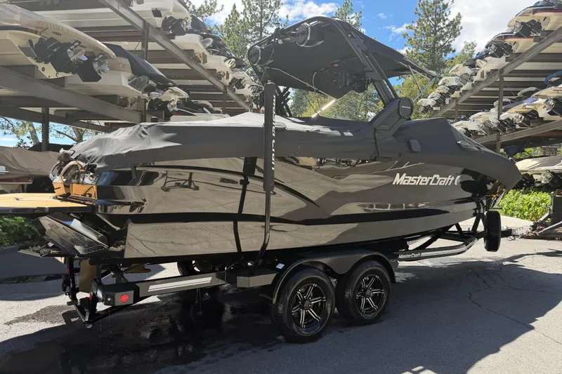 Slide: The Image of 2024 MasterCraft X24 boat covered and parked on a trailer in a marina. - 1