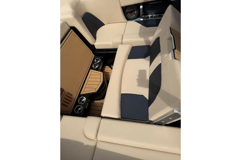 Slide: The Image of 2024 MasterCraft X24 boat interior with beige and black seating, cup holders, and teak flooring. - 10