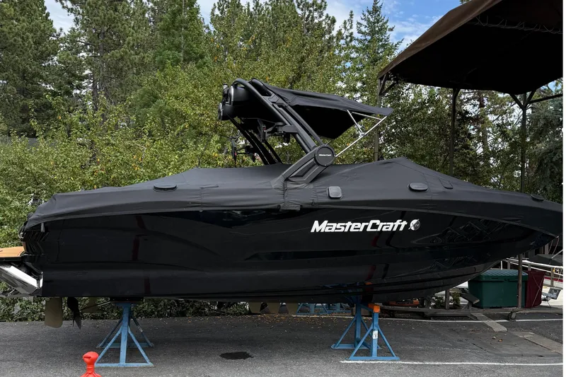 Slide: The Image of A black MasterCraft X24 boat is on stands in a wooded area. - 2