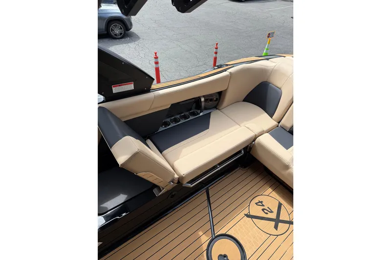 Slide: The Image of 2024 MasterCraft X24 boat interior with beige and black seating, teak flooring. - 12