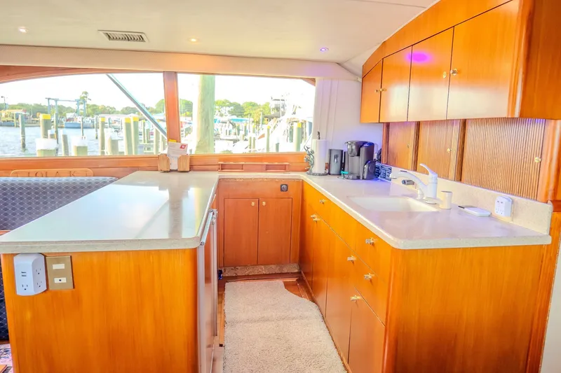 Slide: The Image of Luxurious kitchen interior of 2000 Ocean Yachts 48 Super Sport with wooden cabinetry and marina view. - 28