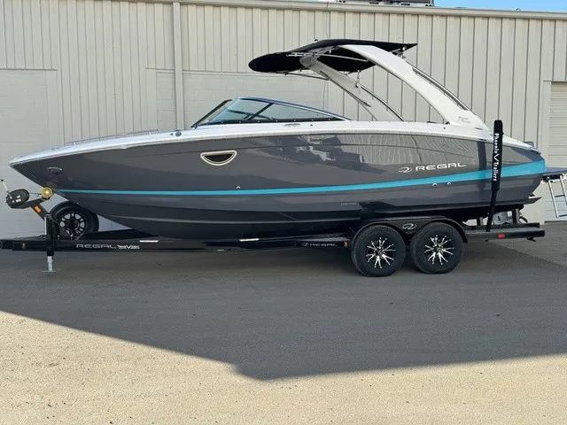 Slide: The Image of A 2024 Regal LS6 boat on a trailer, featuring gray and blue paint, parked by a building. - 10