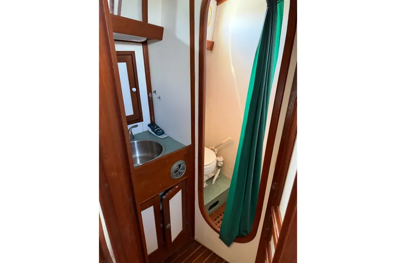 Slide: The Image of 1985 Shannon Ketch yacht bathroom with sink, toilet, and green shower curtain. - 14