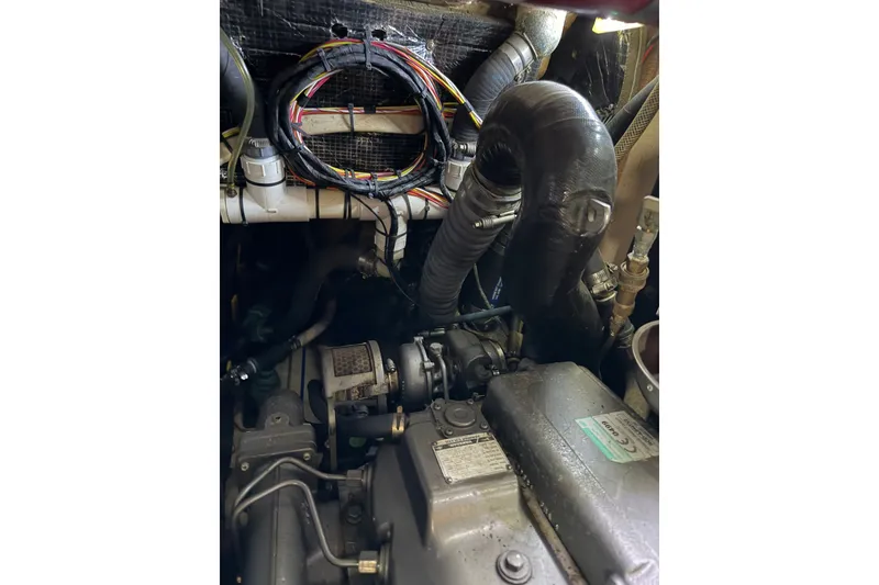 Slide: The Image of Engine compartment of a 1985 Shannon Ketch sailboat, featuring wiring and hoses. - 12