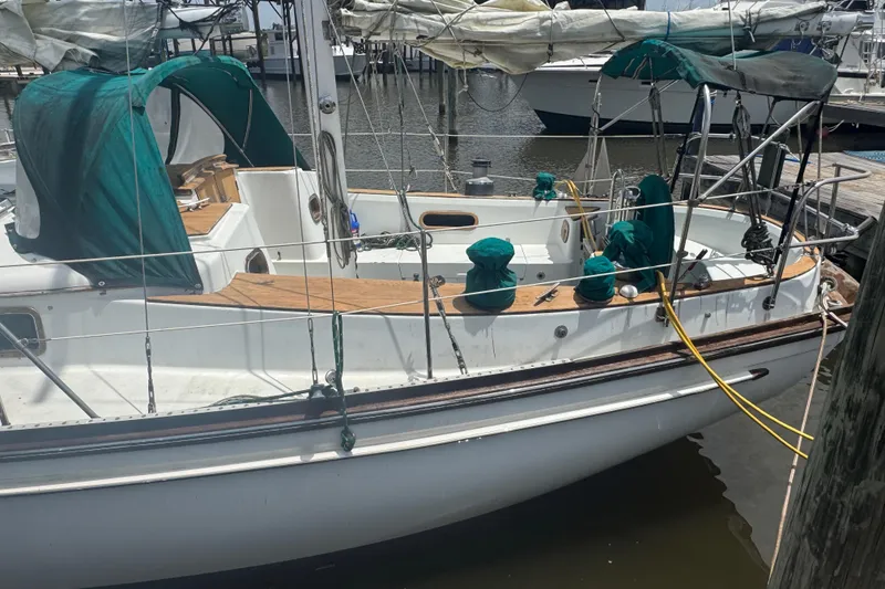 Slide: The Image of 1985 Shannon Ketch sailboat docked, featuring green covers and wooden deck details. - 2