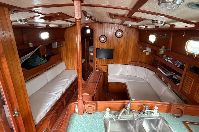 Slide: The Image of Interior of a 1985 Shannon Ketch sailboat with wooden paneling and cozy seating area. - 6
