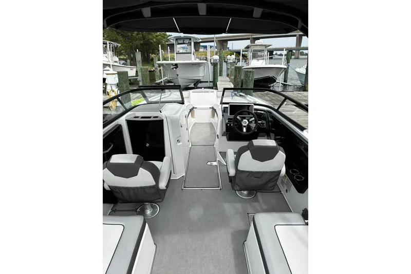 Slide: The Image of 2023 Yamaha Boats AR250 interior with modern seating and steering, docked at a marina. - 28