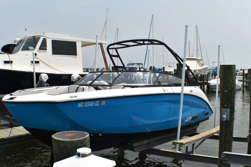 The Image of 2023 Yamaha Boats AR250 in blue, docked at a marina with other boats. - 1