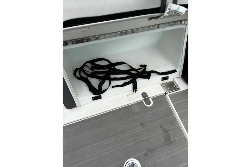Slide: The Image of Open storage compartment in 2023 Yamaha AR250 boat with black straps inside. - 24