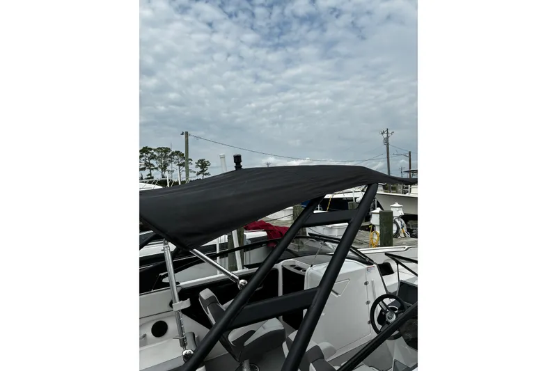 Slide: The Image of 2023 Yamaha Boats AR250 with black canopy, docked under a cloudy sky. - 29