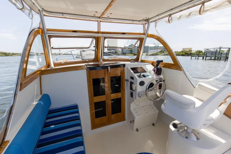 Slide: The Image of 2019 Seaway Seafarer 24 boat interior with helm, striped seating, and waterfront view. - 23