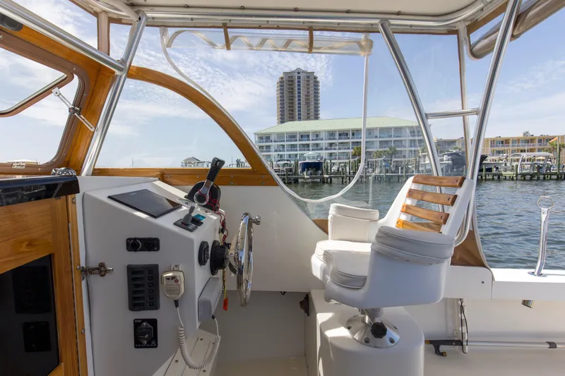Slide: The Image of 2019 Seaway Seafarer 24 boat interior with helm, overlooking marina and waterfront buildings. - 25